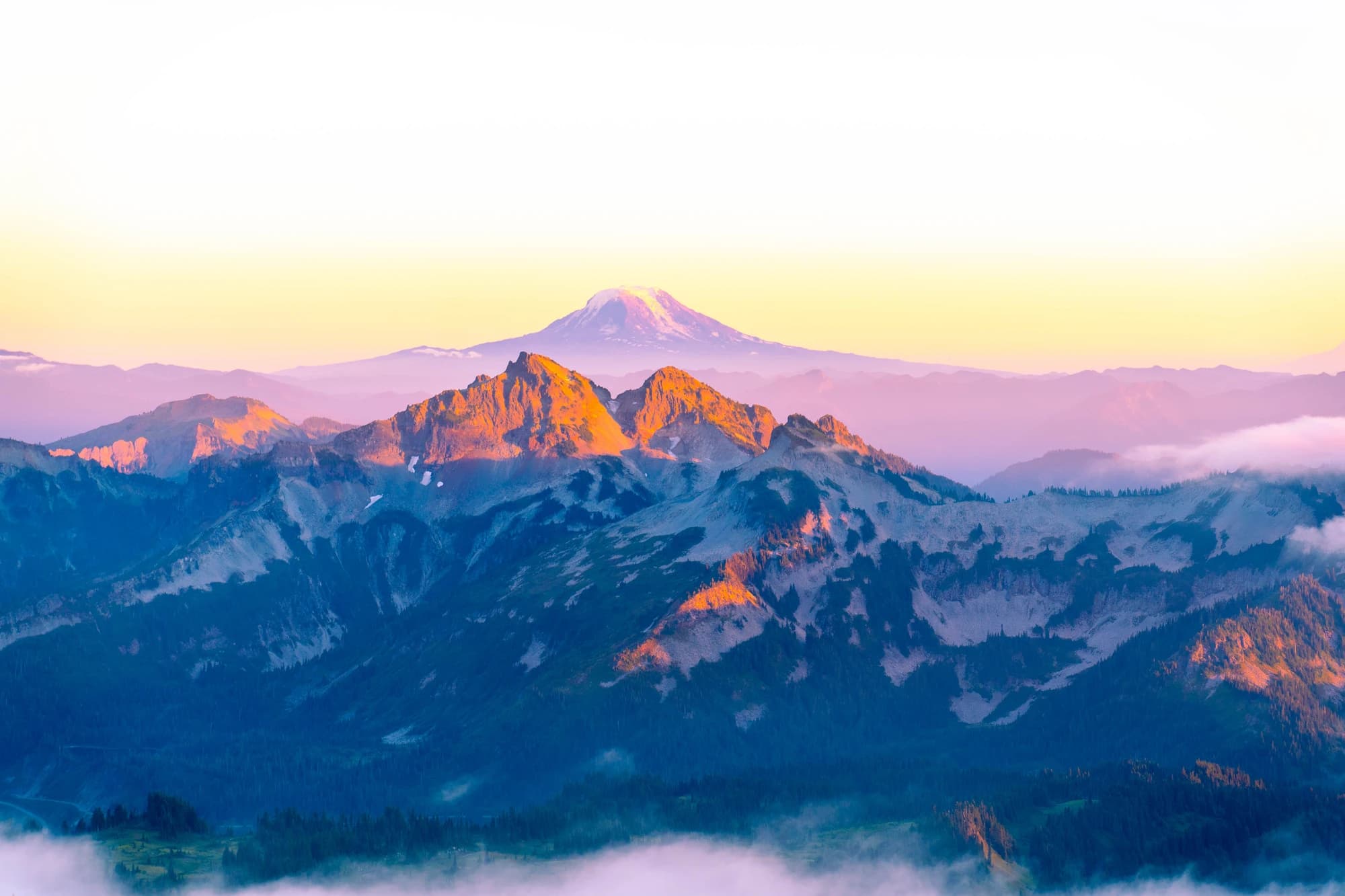 First light on a row of peaks with a snow-capped volcano on the horizon