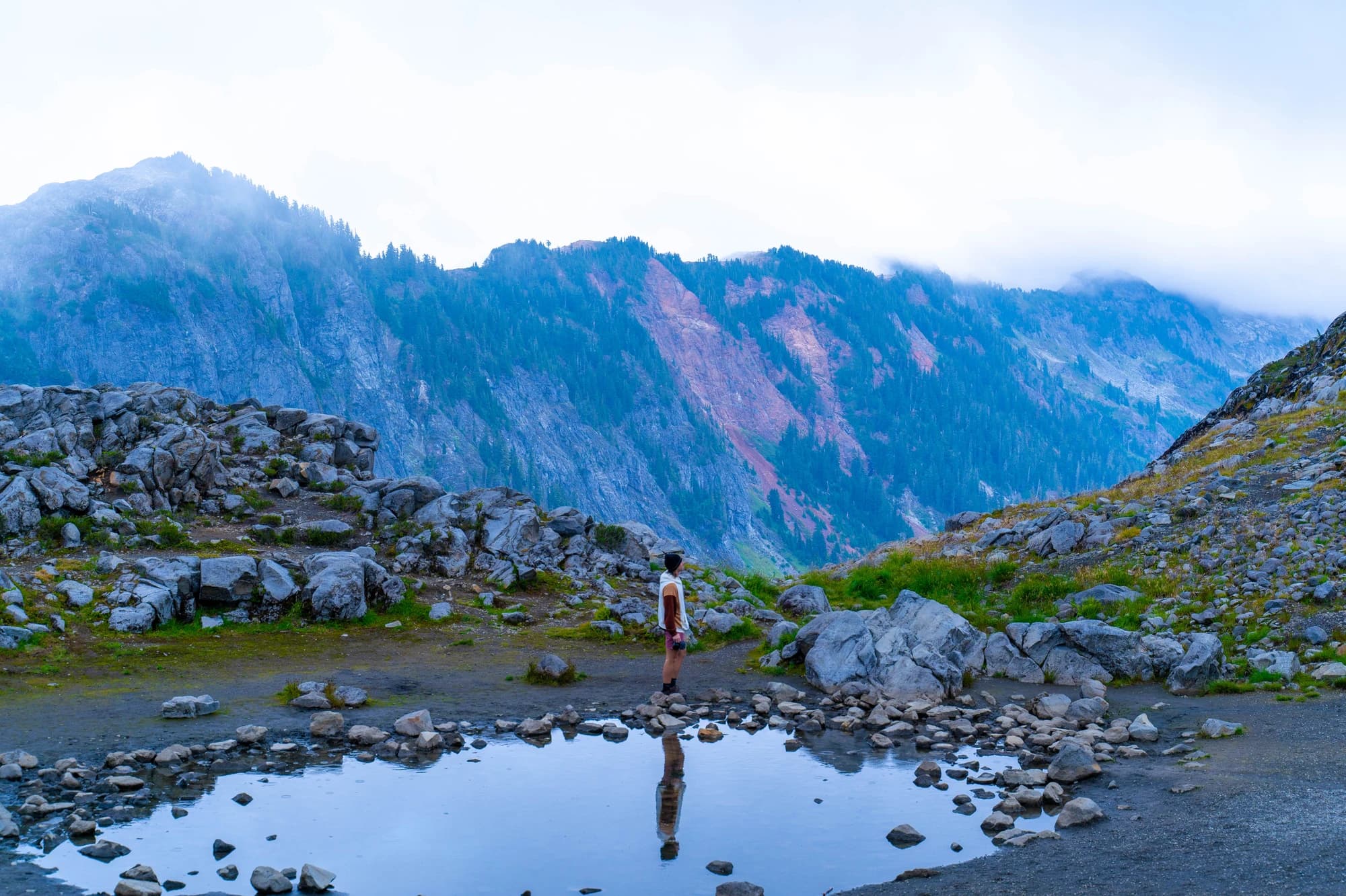 Cam reflected in a still alpine pool below misty mountain walls
