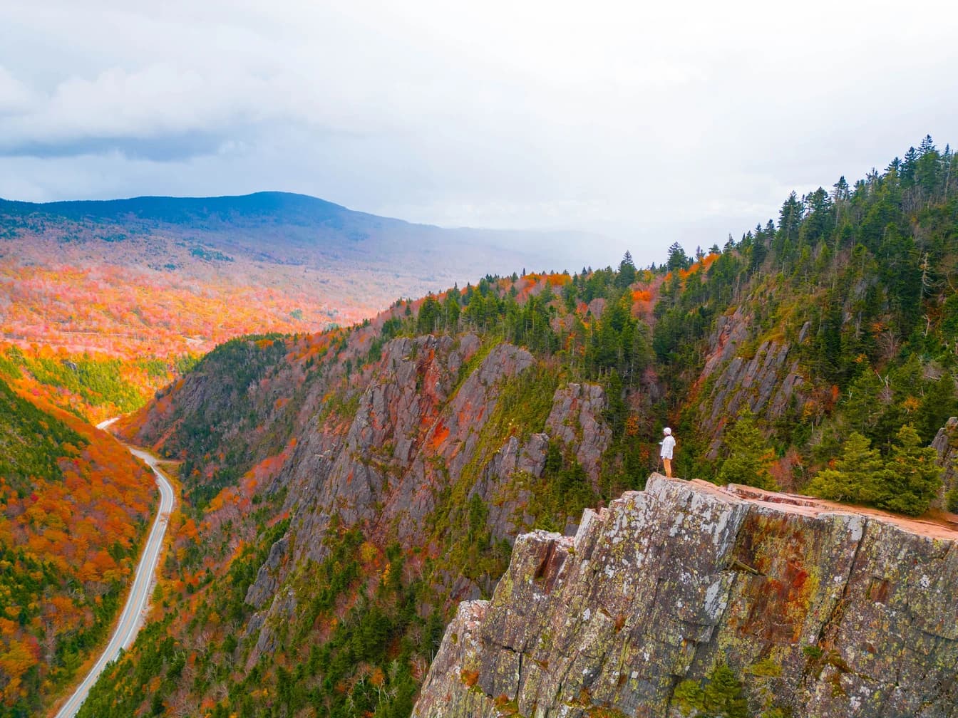 Cam on a cliff edge above a mountain pass in peak autumn colour